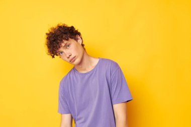 Mor tişörtlü kıvırcık saçlı adam stüdyo sarı arka planda.