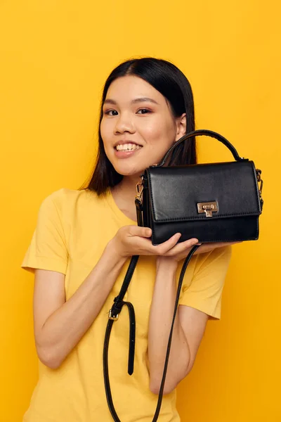 Glad kvinna i en gul t-shirt svart kvinnors väska — Stockfoto