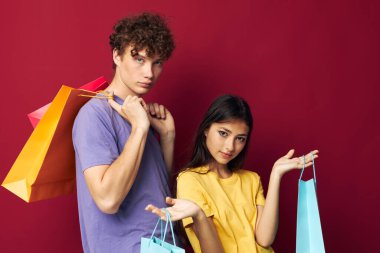 Gençler renkli çantalarla alışveriş yapıyor. Eğlenceli, izole edilmiş bir arka plan.
