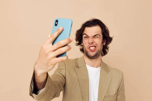 Homem de terno posando emoções olhando para o telefone bege fundo — Fotografia de Stock