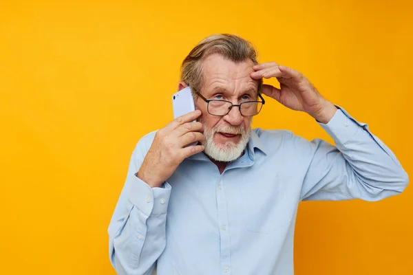 Porträtt äldre man talar på telefonen känslor gul bakgrund — Stockfoto