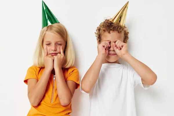 Imagen de chico y chica positivos en gorras multicolores cumpleaños fiesta emoción fondo claro —  Fotos de Stock