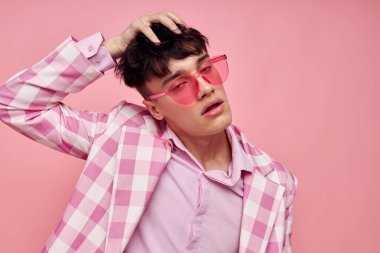 Şık giyinmiş genç bir adam. Ceket giyip, el hareketleriyle kendine güvenen bir model stüdyosu kuruyor.