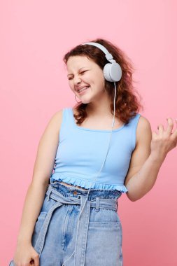 Kulaklık takan güzel bir kadın dikkat dağıtıcı moda dansı pembe arka plan değiştirilmemiş