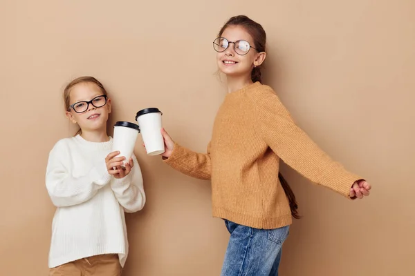 Дві маленькі смішні дівчата склянка з напоєм бежевий фон — стокове фото