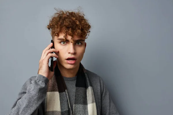 Pohledný chlap v kostkované šálu mluvit do telefonu pózování emoce světlo pozadí — Stock fotografie
