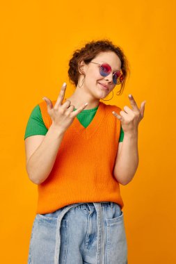 Güzel kadın turuncu kazaklar güneş gözlükleri çok renkli gözlükler sarı arka plan değiştirilmemiş.