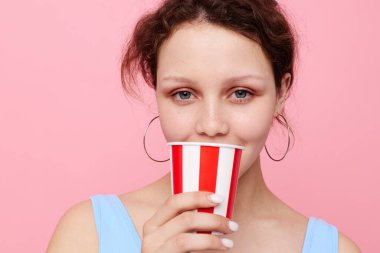 Pembe arka planda tek kullanımlık çok renkli camları olan neşeli bir kız.