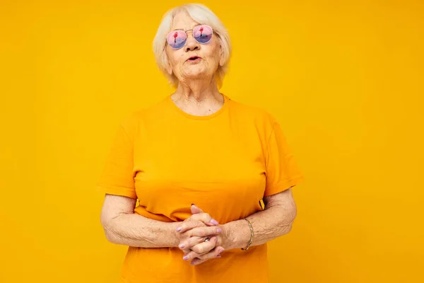 Sarı tişörtlü emekli bir kadının sarı arka plan pozu. — Stok fotoğraf