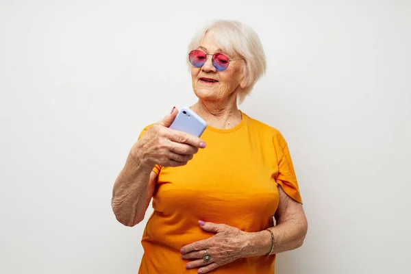 노란 티셔츠를 입고 전화 감청 감정에 의해 대화를 나누는 은퇴 한 할머니의 사진 — 스톡 사진