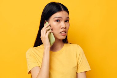Asyalı görünümlü kadın telefon iletişimi eğlenceli sarı arkaplan kullanın