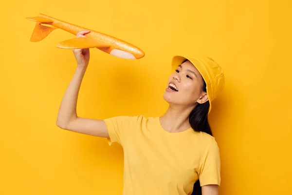 亚洲的女人，手里拿着一个黄色的平面，一个独立的玩具，背景不变 — 图库照片