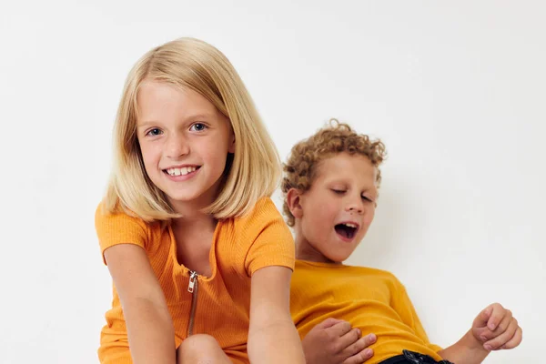 Imagen de niño y niña positivos en camisetas amarillas de pie lado a lado emociones de la infancia inalteradas — Foto de Stock