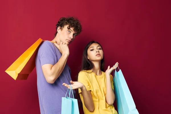 Portrait of a man and a woman in colorful T-shirts with bags Shopping isolated background unaltered — Stockfoto