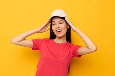 Güzel esmer, kırmızı tişörtlü, başında şapkası olan.