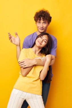 rengarenk tişörtlü gençler dostluk pozu veriyorlar. Sarı arka plan değişmemiş.