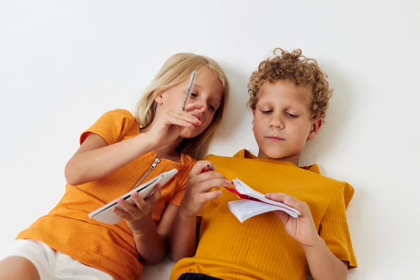 Portret van schattig liggen op de vloer met notitieblokken en potloden geïsoleerde achtergrond ongewijzigd — Stockfoto