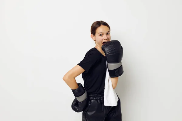 穿着黑裤子和背景T恤的拳击手套的女运动员 — 图库照片