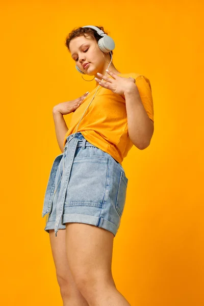Csinos nő sárga póló fejhallgató szórakozás zene szórakozás sárga háttér változatlan — Stock Fotó