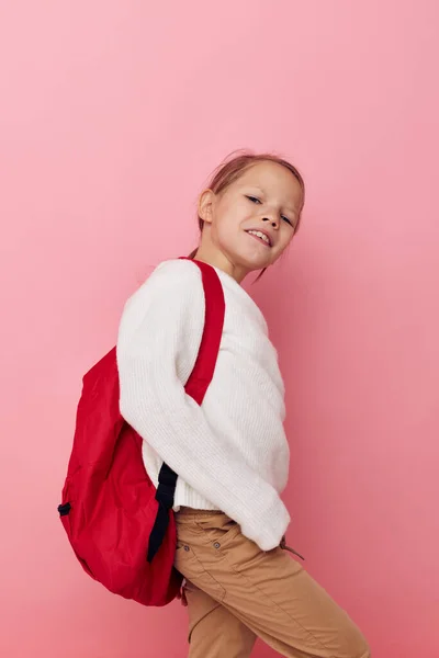 Klein meisje met een rode rugzak plezier geïsoleerde achtergrond — Stockfoto