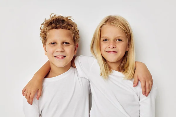 흰색 티셔츠를 입은 귀여운 아이들의 모습 이 베이지 색 배경 옆에 서 있다 — 스톡 사진