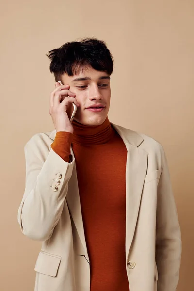 Un joven posando con un teléfono en sus manos en una chaqueta elegante modelo de estudio — Foto de Stock