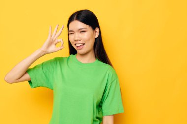Asyalı kadın yeşil t-shirt pozu veriyor. Duygular, fotokopi alanı izole edilmiş arka plan değiştirilmemiş.