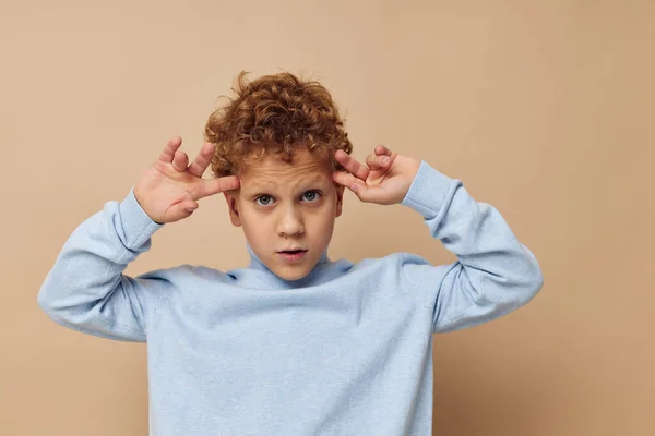 Kudrnatý chlapec v modrém svetru pózuje zábavné dětství v nezměněné — Stock fotografie