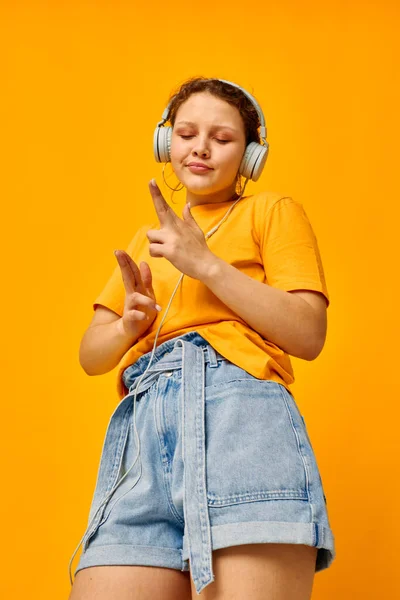 Retrato de uma jovem mulher amarelo t-shirt fones de ouvido entretenimento música diversão recortada vista inalterada — Fotografia de Stock