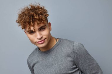 Gri kazaklı yakışıklı adam. Moda stüdyosu. Gri arka plan.