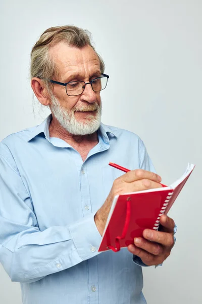 Foto van gepensioneerde oude man schrijft emoties in een notebook onveranderd — Stockfoto