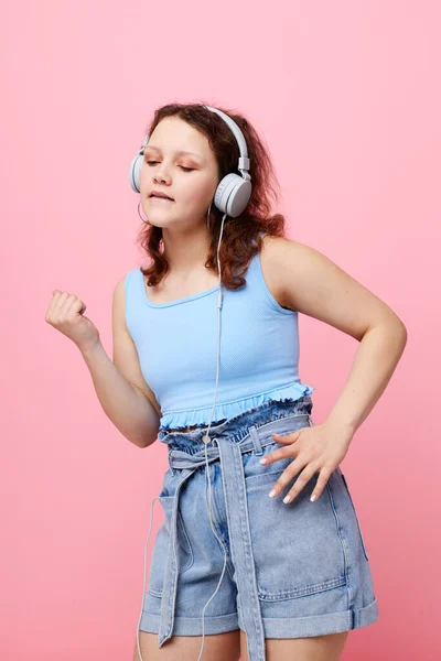 Χαρούμενη γυναίκα με τζιν σορτς φορώντας ακουστικά τεχνολογία ψυχαγωγίας μόδας αναλλοίωτη — Φωτογραφία Αρχείου