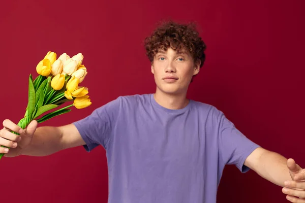 Молодий хлопець тримає жовтий букет квітів фіолетові футболки ізольований фон незмінний — стокове фото