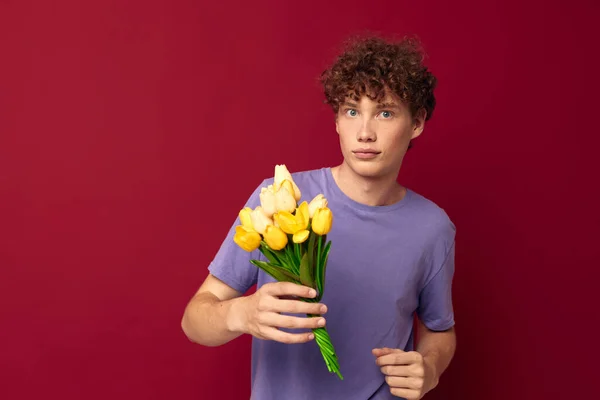 Adolescente segurando um buquê amarelo de flores roxo camisetas vermelho fundo inalterado — Fotografia de Stock