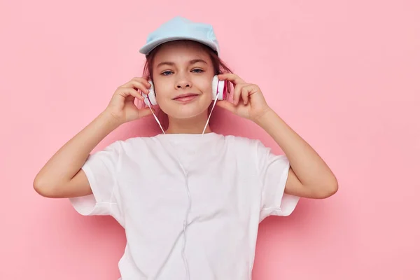 Χαριτωμένο κορίτσι ακουστικά σε ένα λευκό t-shirt και ένα καπάκι Lifestyle αμετάβλητη — Φωτογραφία Αρχείου
