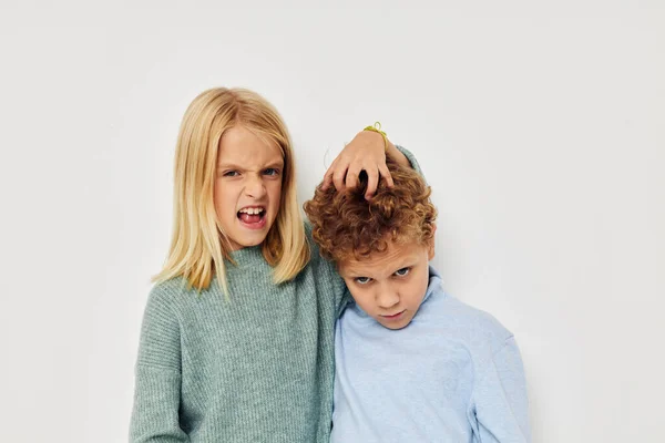 Photo of two children in multi-colored sweaters posing for fun light background — Stock Photo, Image