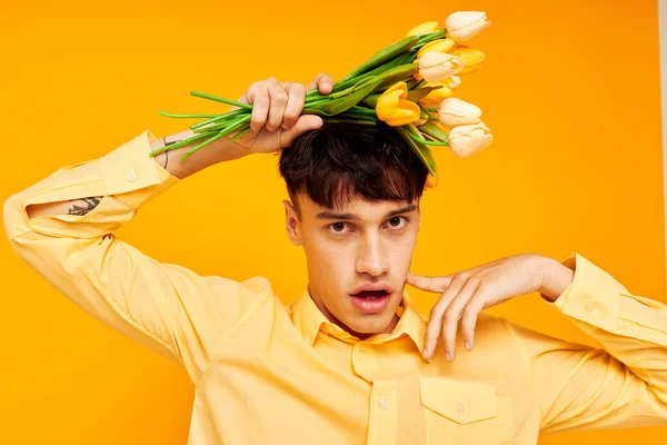 Foto de romántico novio joven con un ramo de flores posando un fondo amarillo regalo inalterado — Foto de Stock