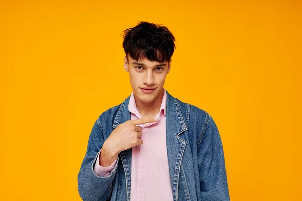 Hombre guapo en chaqueta de mezclilla estilo joven posando fondo amarillo — Foto de Stock