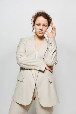 Genç bir kadının portresi. Şık giyiniyor. Moda stüdyosunun açık arka planı değişmemiş.