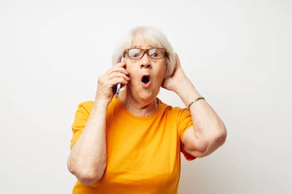 Foto de idosa aposentada em óculos casuais de t-shirt conversando no fundo isolado do telefone — Fotografia de Stock