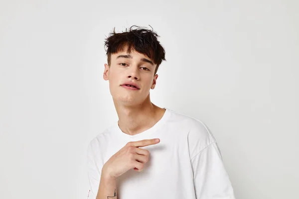 Porträtt av en ung man modern ungdom stil vit t-shirt tatuering på armen ljus bakgrund oförändrad — Stockfoto
