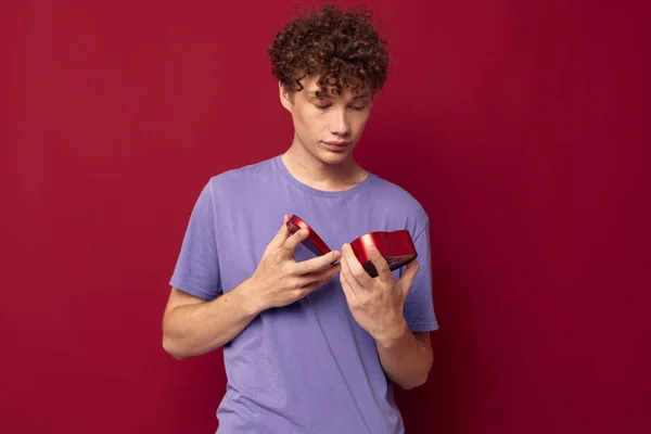 Söt lockig kille i lila t-shirt hjärta formad låda gåva — Stockfoto