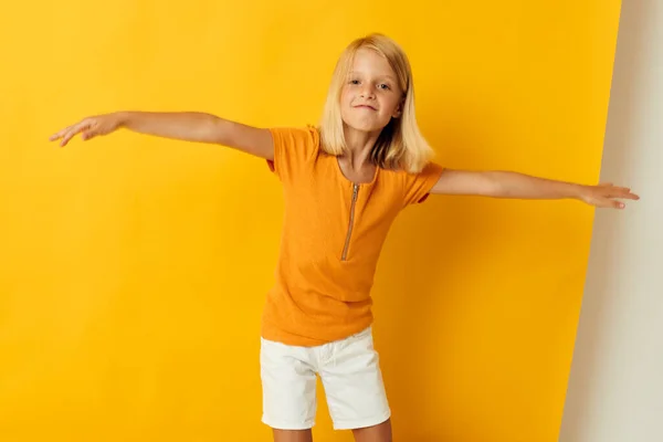 Mała dziewczynka uśmiech strony gesty pozowanie casual nosić zabawy żółty tło bez zmian — Zdjęcie stockowe