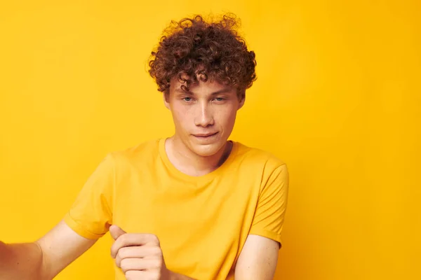 Retrato de un joven rizado con elegante camiseta amarilla posando fondo amarillo inalterado — Foto de Stock