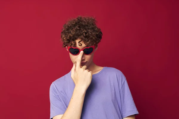 Retrato de un joven rizado hombre en una camiseta púrpura con gafas de sol posando estilo juvenil — Foto de Stock