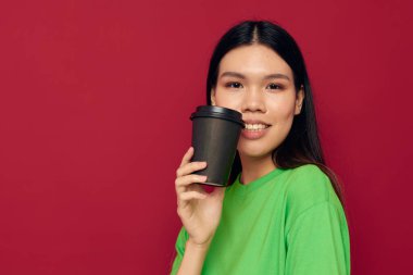 Asyalı kadın yeşil tişörtlü, tek kullanımlık siyah gözlükle poz veriyor. Stüdyo modeli değiştirilmemiş.