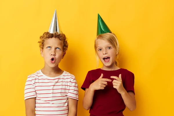 Фотография положительный мальчик и девочка праздник весело с шапками на голове изолированный фон — стоковое фото
