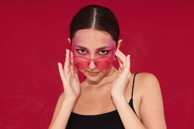 Pembe gözlüklü seksi esmer kadın makyaj duyguları kozmetik olarak izole edilmiş.