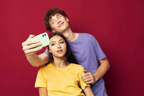 Uomo e donna in T-shirt colorate con uno sfondo isolato telefono — Foto Stock