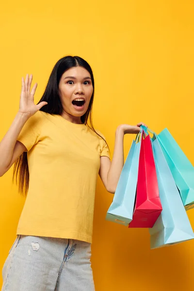 Vrouw in een geel T-shirt met kleurrijke boodschappentassen geïsoleerde achtergrond ongewijzigd — Stockfoto